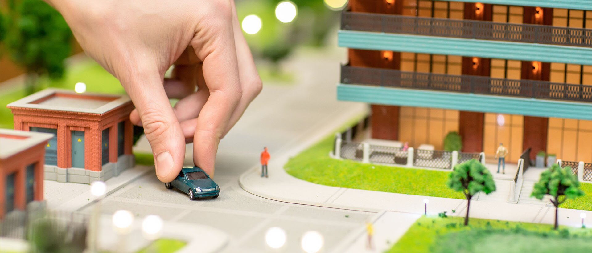 Diorama einer Hand, die ein Spielzeugauto durch Modellstadt fährt | © Shutterstock